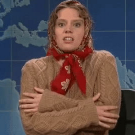 woman in brown jumper and red scarf shivering and rubbing her arms together as she is cold